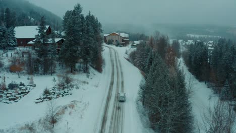 drone zoom forward tracking truck driving up snowy hillside road