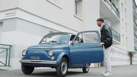 low-angle shot of a man entering an antique car with a duffel bag