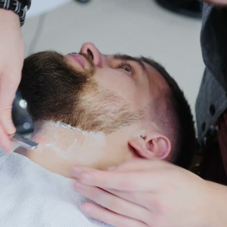 peluquero usando cuchilla de afeitar para afeitar el cuello del cliente