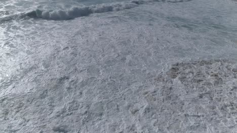 Aerial-view-beautiful-beach-with-views-of-ocean-waves-and-water-crashing-on-to-sandy-beach