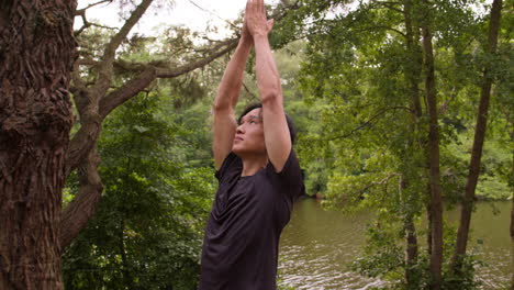 man wearing sports clothing doing yoga on mat in forest by lake or river enjoying peace and beauty of nature 3