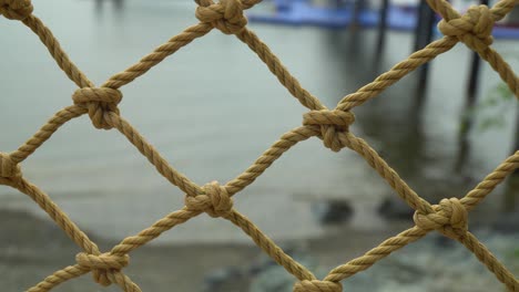 rope net fence on seashore of beach with calm water in the background