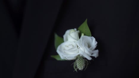 white flower boutonniere on a black suit