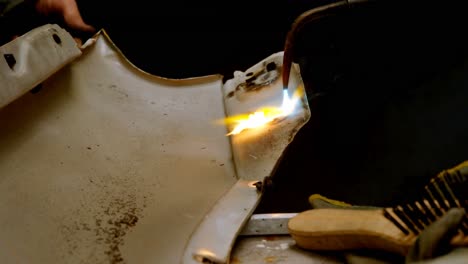 mechanic using wielding torch on a car part 4k