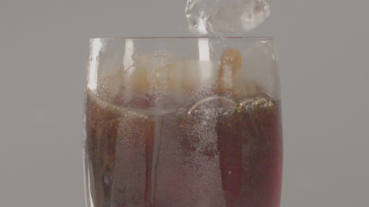 primer plano de cubitos de hielo cayendo en un vaso de cola en cámara lenta - 240 fps
