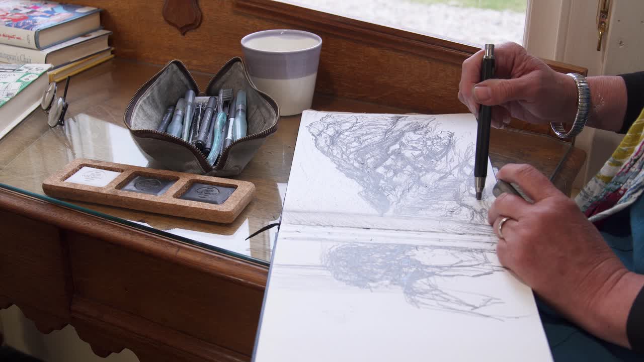 Handheld shot of an artist drawing in a sketchpad using a pencil