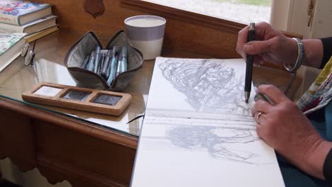 handheld shot of an artist drawing in a sketchpad using a pencil