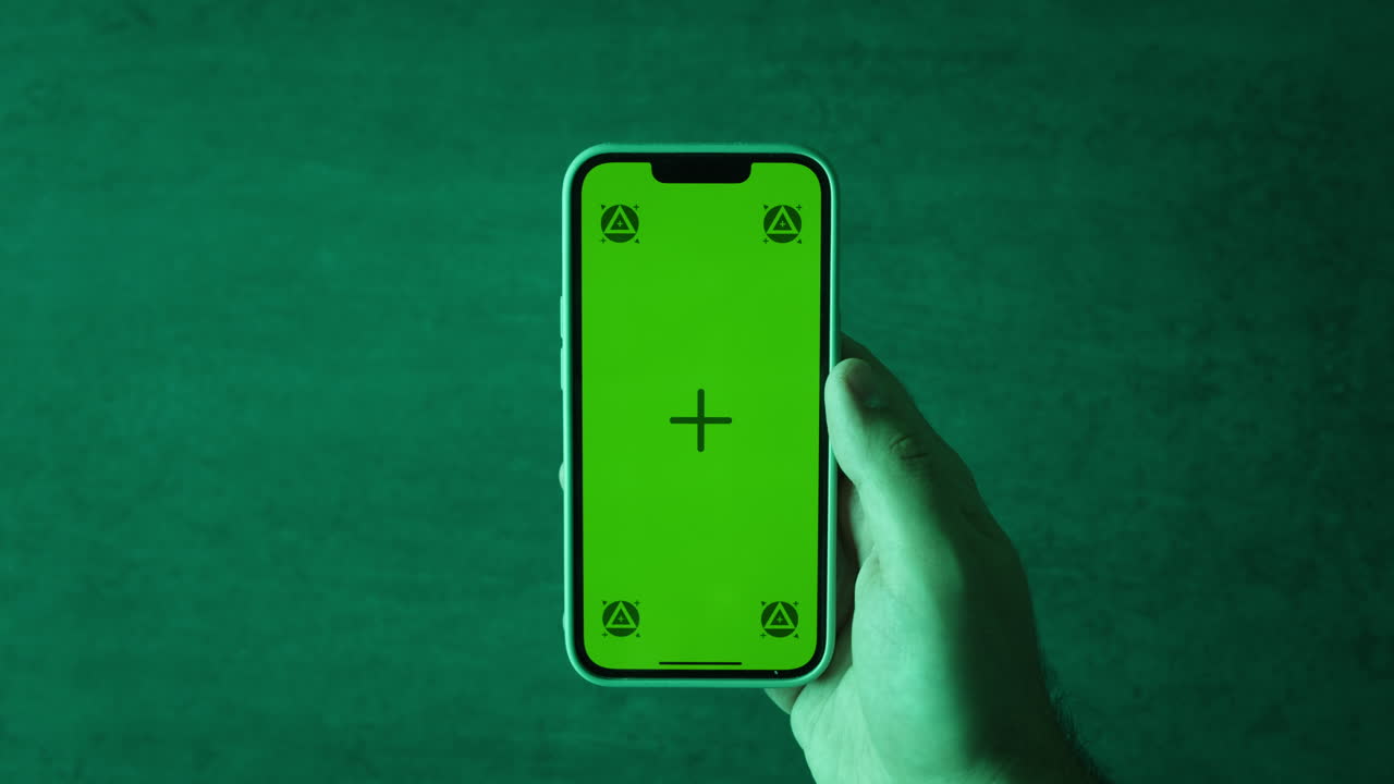 persona que sostiene un teléfono inteligente con pantalla verde para grabar video