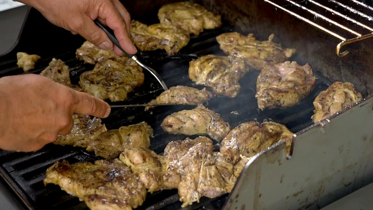 Cooking chicken on a bbq, cutting chicken pieces into smaller portions