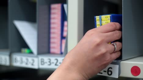 Close-up-of-latino-or-caucasion-female-hand-picking-package-from-wharehouse-shelf