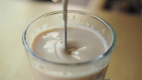 stirring a latte in a glass