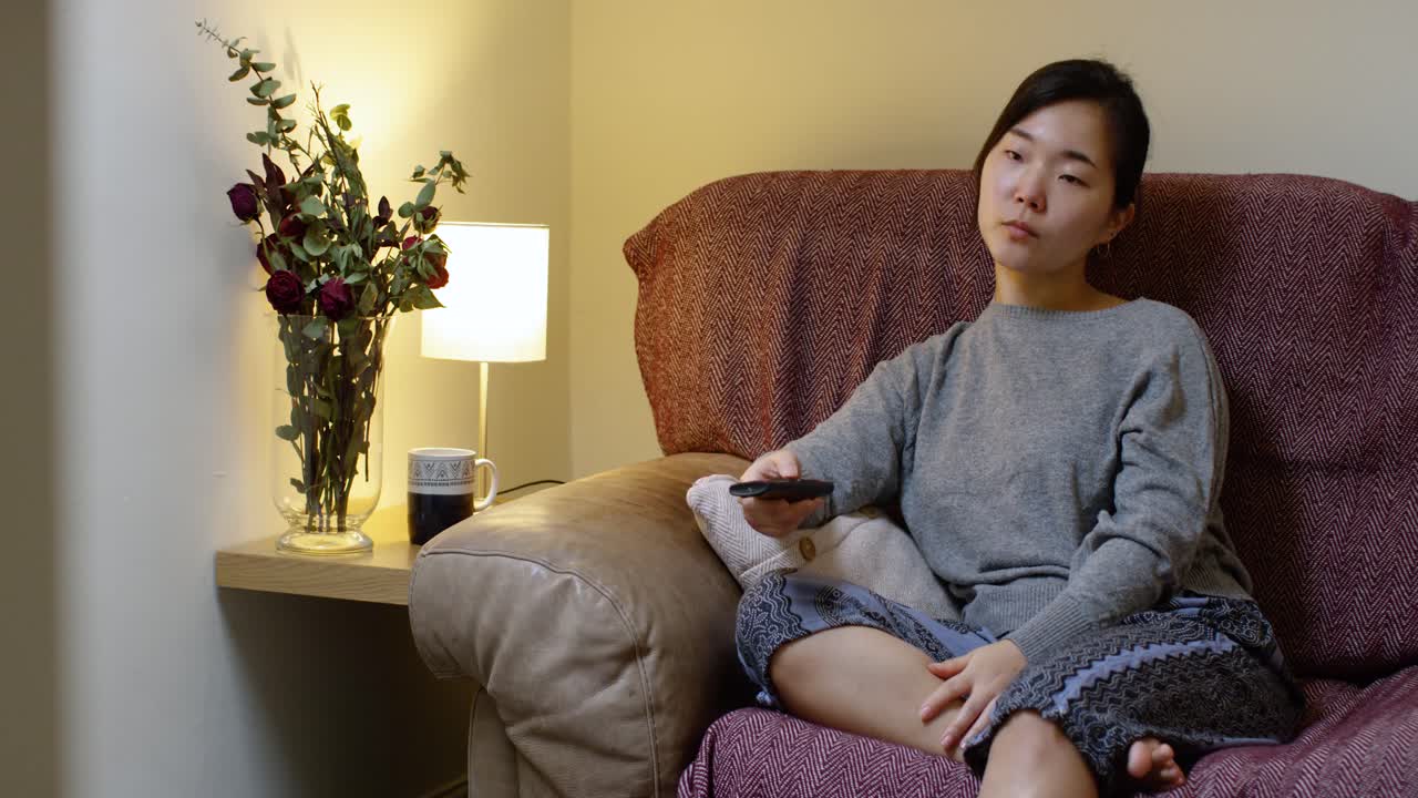 Bored Asian Woman Watching TV In Self-Isolation During Corona Virus