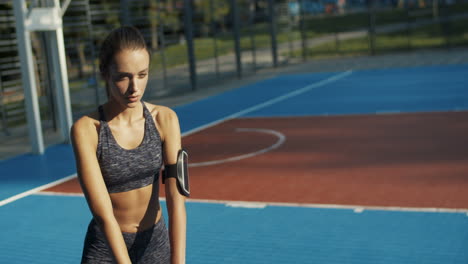 chica fitness haciendo sentadillas en la cancha deportiva en la mañana de verano