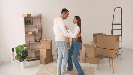 vista frontal de una joven pareja feliz descalza bailando juntos en una alfombra en una casa nueva 1