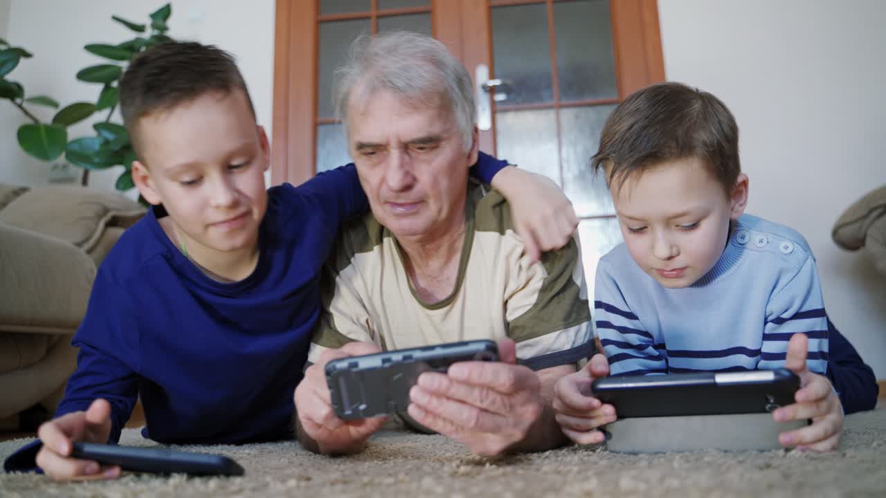 Parents playing on phone together. Little boys with grandfather using smartphone at home