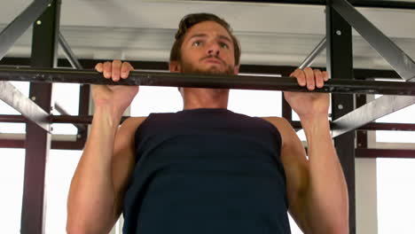 fit man doing pull ups in fitness studio