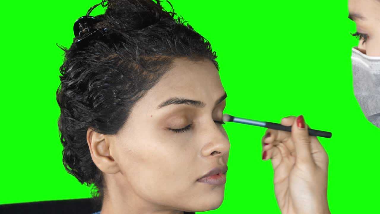 artista de maquillaje aplicando sombra de ojos en los ojos de la modelo