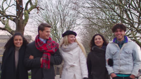 friends walking along south bank on winter visit to london