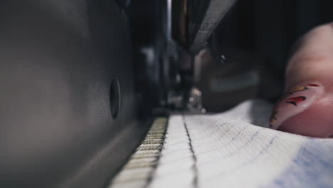 seamstress sews textile medical mask with machine in shop