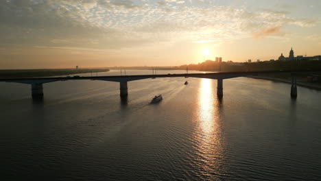 boats on a river at sunset with a city bridge and skyline