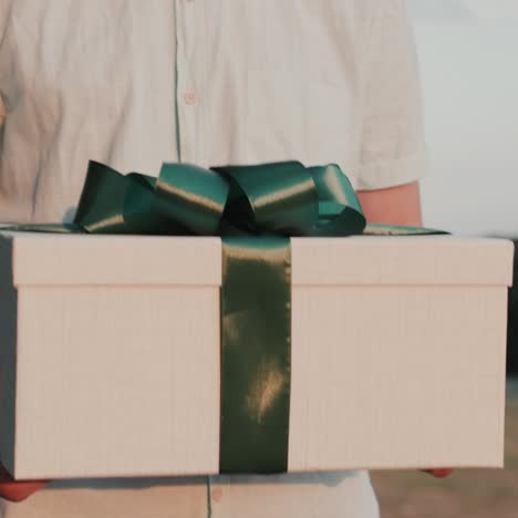 Ein-Mann-Trägt-Eine-Schachtel-Mit-Einem-Geschenk,-Das-Wunderschön-Mit-Klebeband-Verpackt-Ist