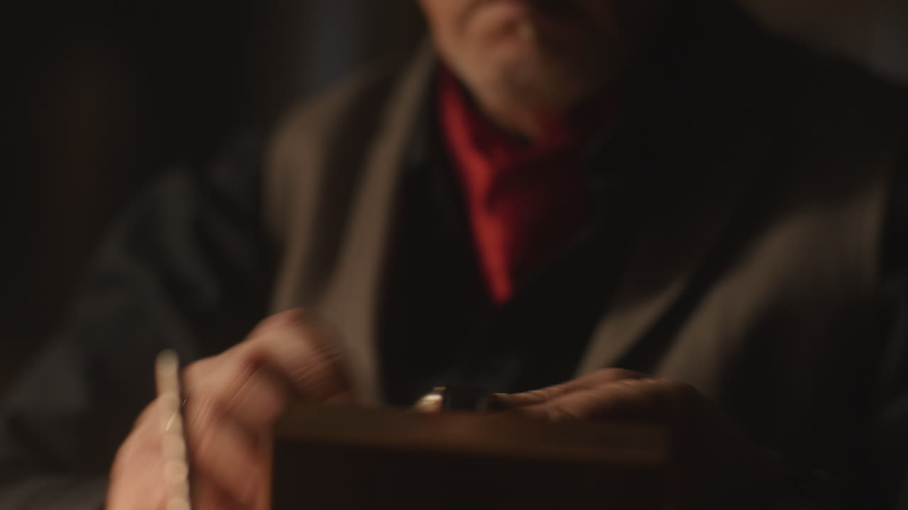 Un uomo anziano e appassionato esamina un vecchio orologio nel suo ufficio di notte.