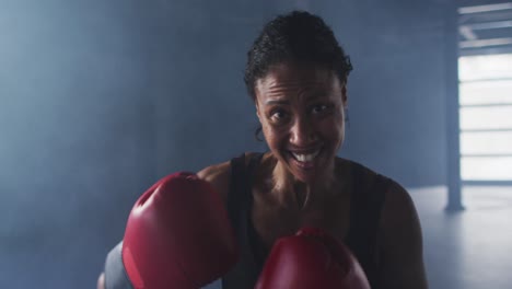 african american woman wearing boxing gloves training throwing punches in empty room