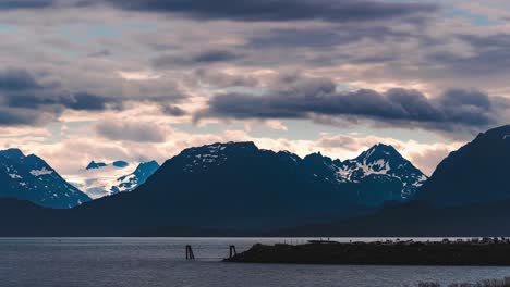 Stunning-golden-hour-Alaskan-sunset-timelapse-over-snow-capped-mountain-range-along-the-ocean-shore