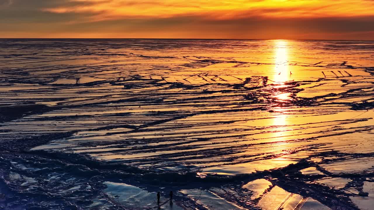 Frossent hav, der reflekterer den gyldne sol ved horisonten, med fjerne figurer på brudt is.