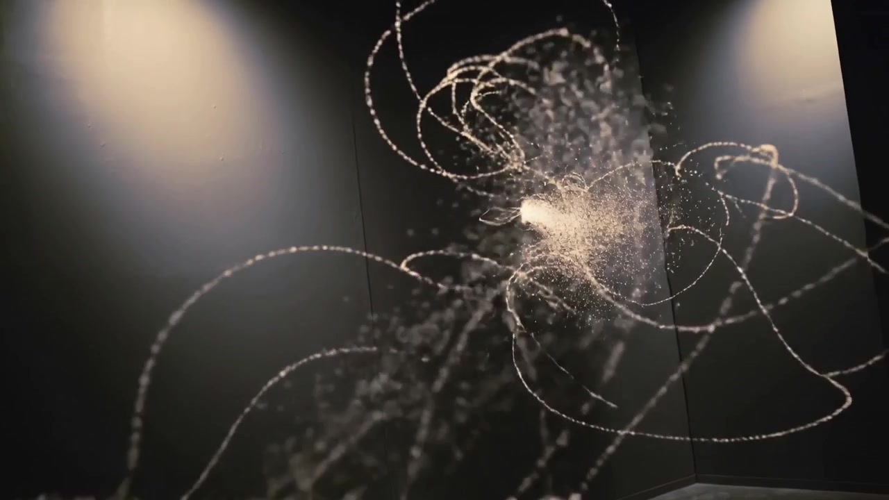Von links kommend, zieht sich ein Partikelband in einer Galerieecke zu einem Knoten zusammen und bildet eine treibende Wolke.