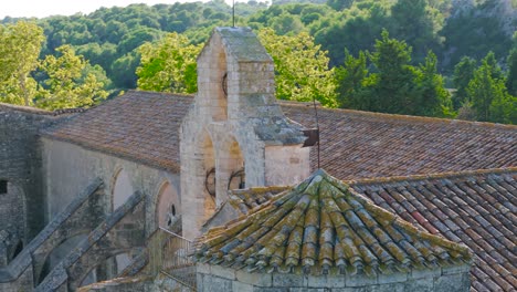 slow orbiting shot of a french abbey with a bell tower surrounded by trees