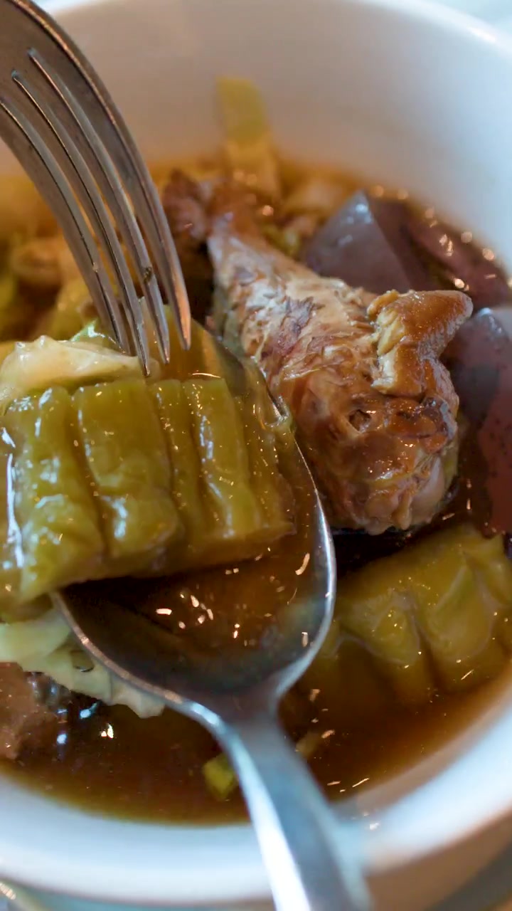 Primo piano di un cucchiaio che solleva melone amaro da una saporita zuppa di noodle di pollo thailandese.