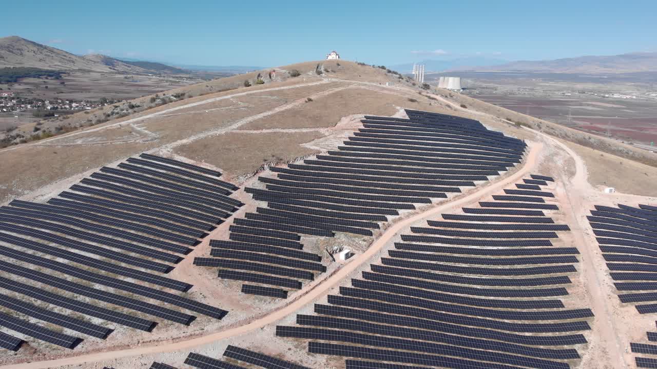 avión no tripulado sobre órbita parque de energía solar fotovoltaica fila de paneles planta de energía de carbón de la colina fondo