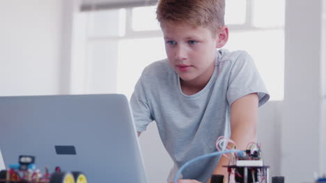 Estudiante-Masculino-Construyendo-Y-Programando-Un-Vehículo-Robot-En-Clase-De-Codificación-De-Computadoras-Después-De-La-Escuela