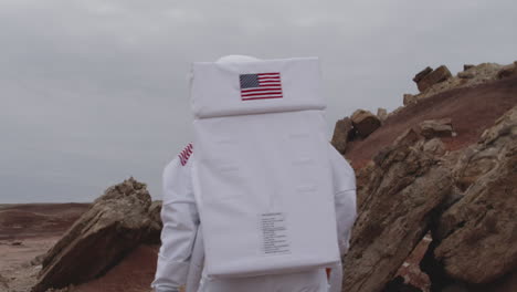 a person wearing an astronaut suit walks across a rocky terrain