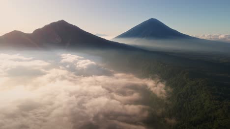 aerial view around low hanging clouds with gunung batur volcano background, sunny morning in bali, indonesia