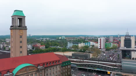 Two-coupled-units-of-Intercity-express-train-arriving-to-train-station.-Aerial-view-of-traffic-in-city.-Fly-around-historic-town-hall-building.-Berlin,-Germany