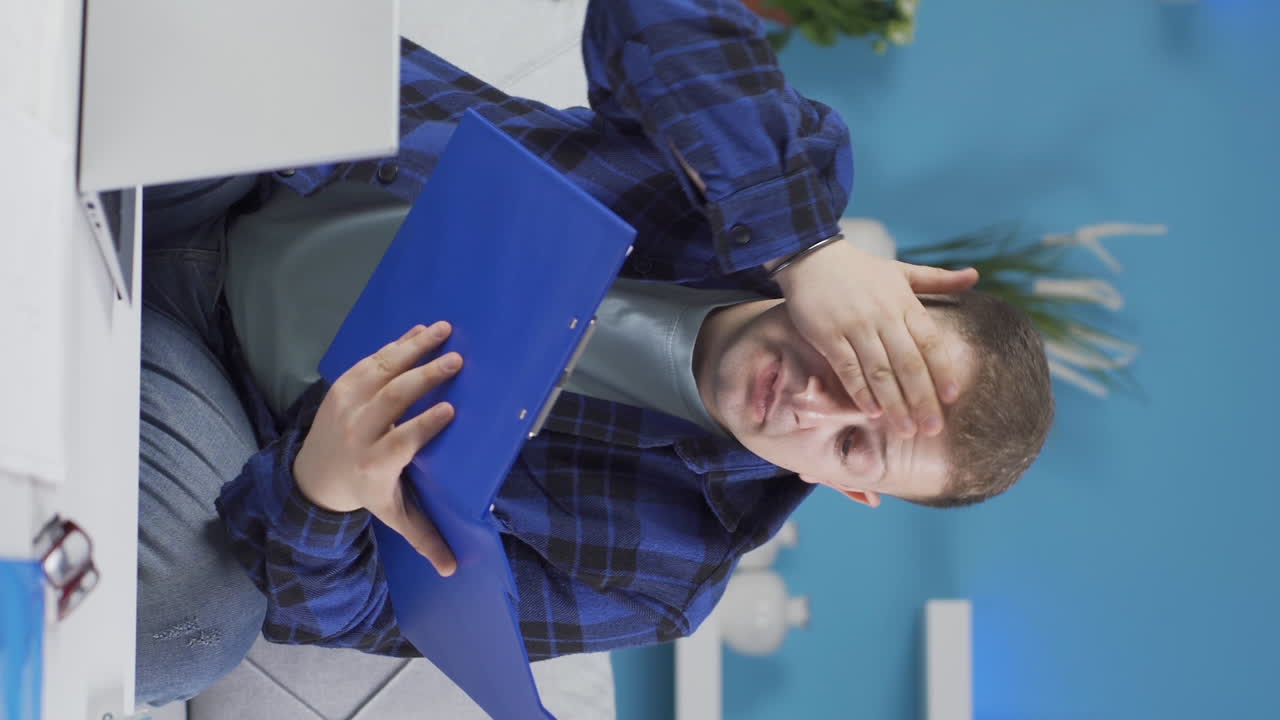 vídeo vertical de un hombre que trabaja en una oficina en casa teniendo un ataque al corazón.