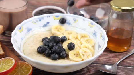 healthy and delicious breakfast with oatmeal, banana, blueberries, and honey