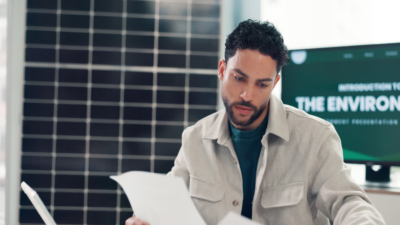 Man Working on Tablet and Papers in an Eco-Friendly Office