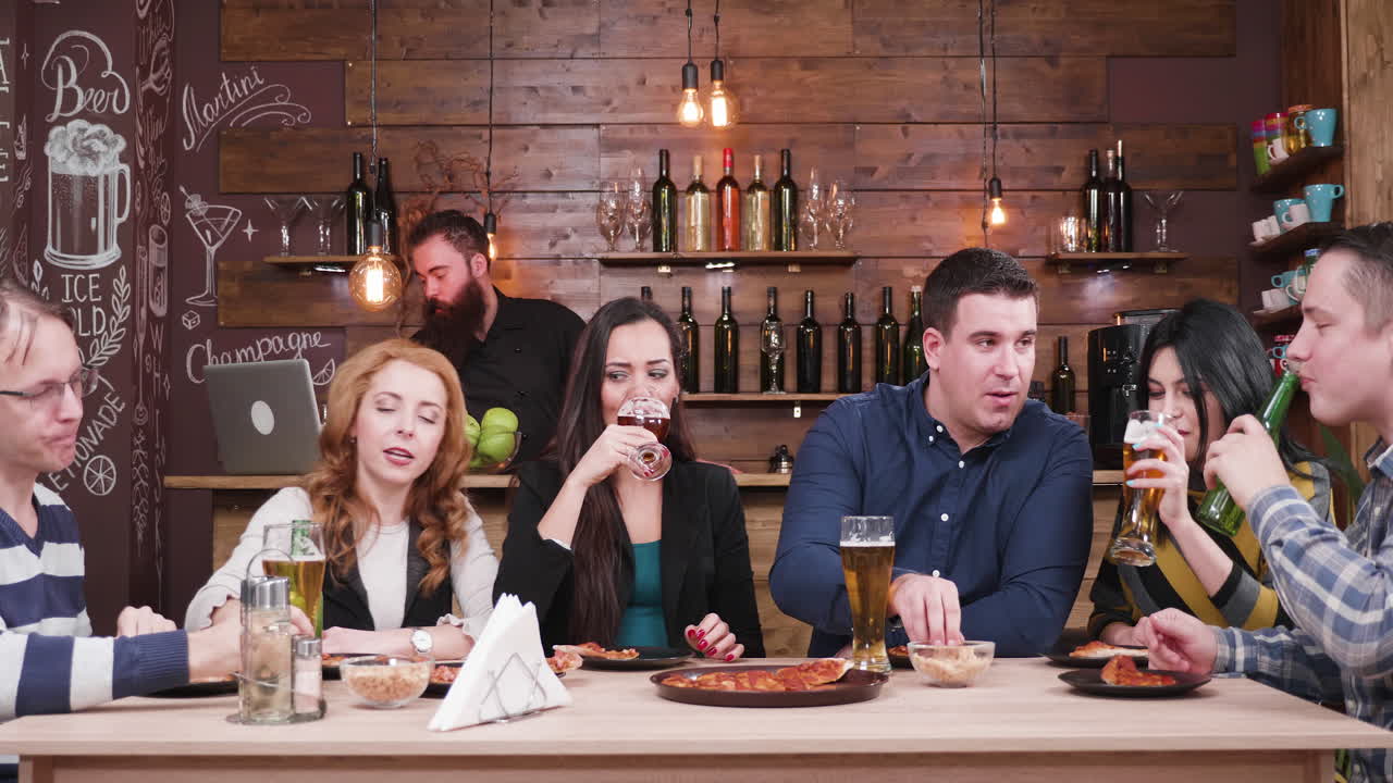 Friends Celebrating with Drinks and Pizza at a Bar