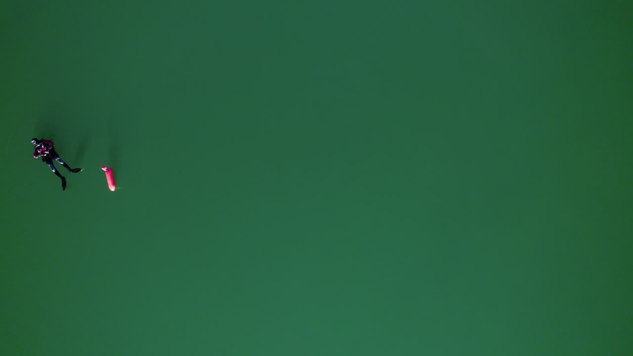 experiencia pacífica de buceo: buzo con tanque de oxígeno flotando en una boya roja en un lago