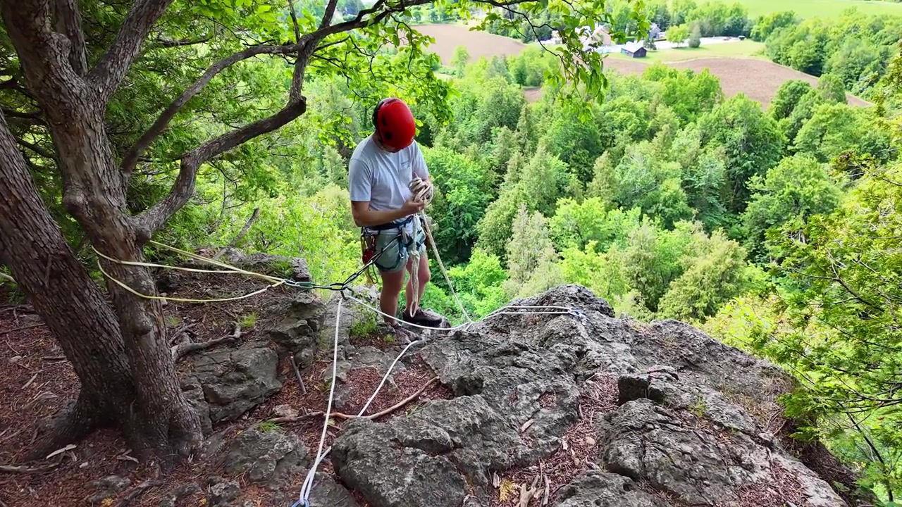 Climber managing his rope at the top of the Rattlesnake Point cliff in Ontario, Canada