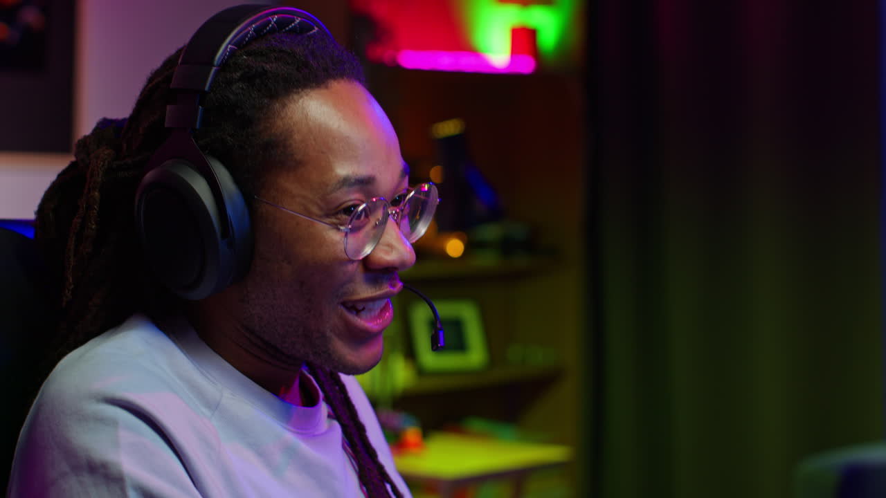 Man playing video games with headphones and microphone, smiling and looking excited