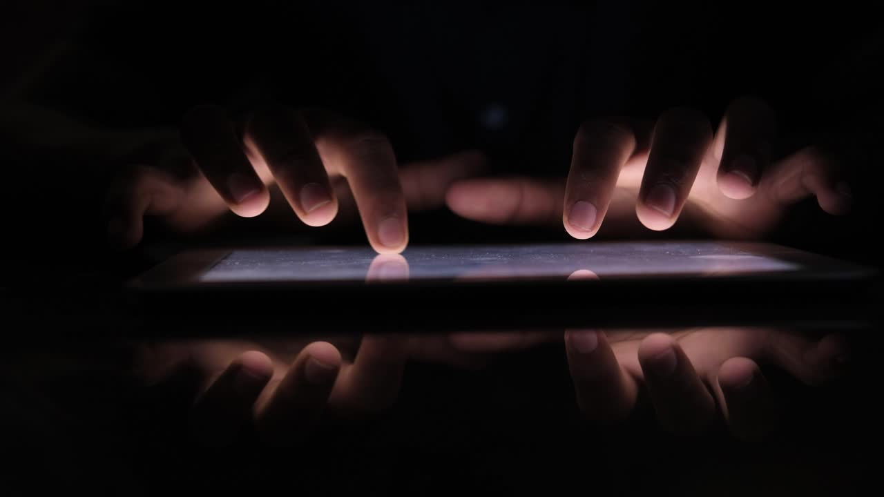 usando una tableta en las manos oscuras