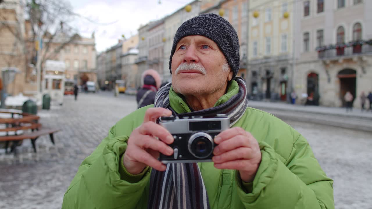 anciano abuelo feliz tomando fotos con una cámara de fotos, sonriendo usando un dispositivo retro al aire libre