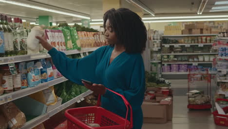 a woman shops for groceries in a supermarket, using her phone to check products