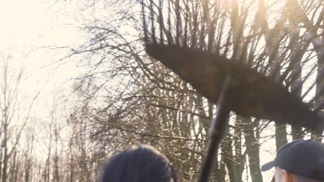 rear view of a caucasian woman holding a rake while walking with her partner throught the countryside