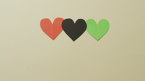 Video-of-red,-black-and-green-paper-hearts-on-beige-background