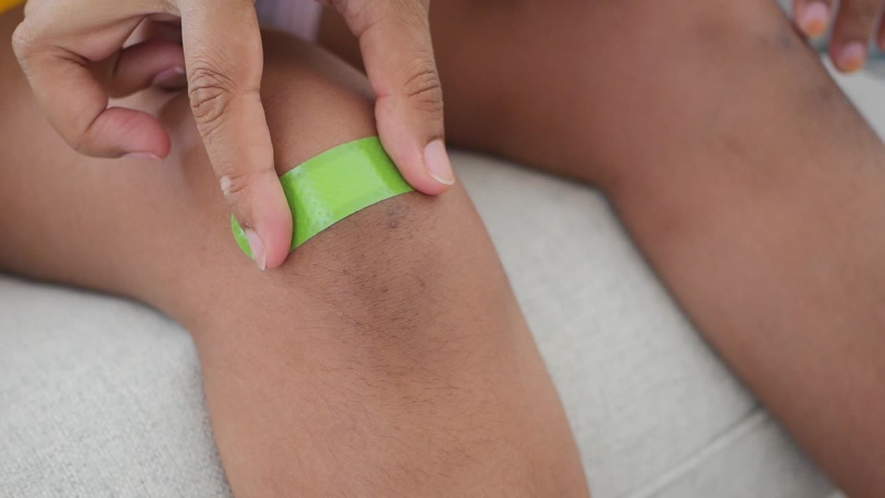 Person applying a band-aid to their knee